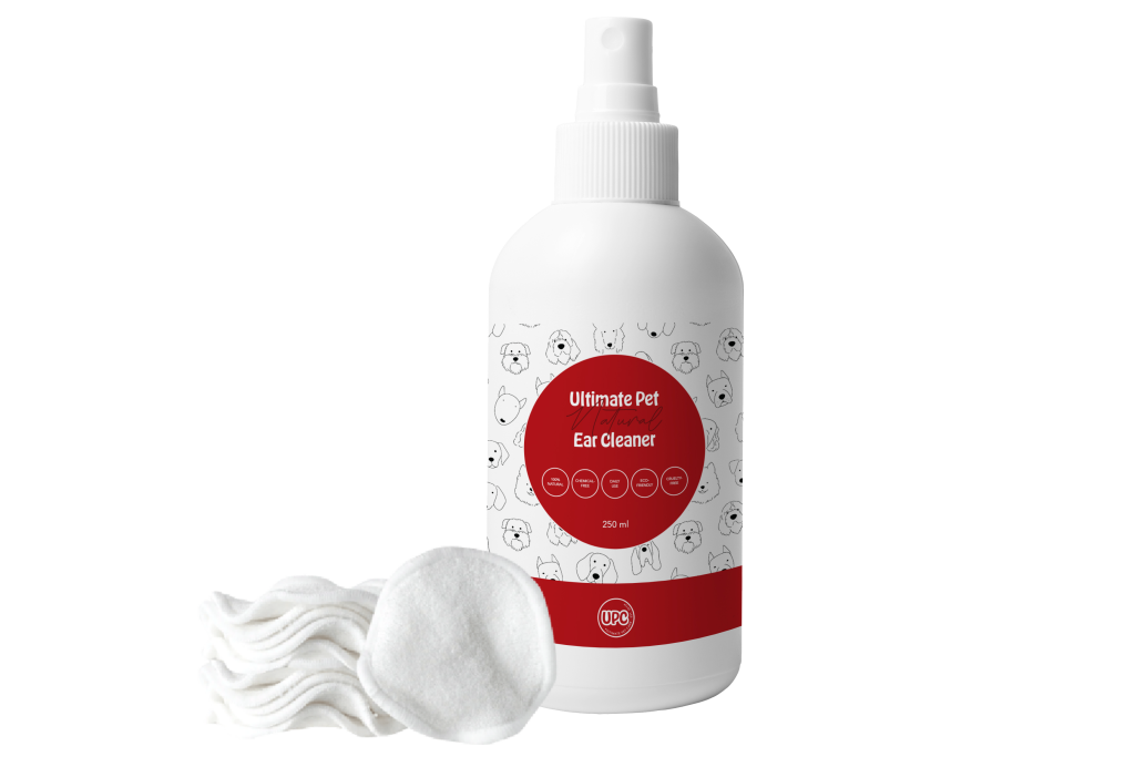Ultimate Pet Care Natural Ear Cleaner 250 ml spray bottle with a white label featuring illustrated dog faces and a red logo, displayed alongside a stack of white cotton pads on a transparent background.